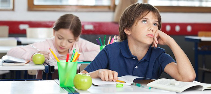 Boy sits at school, but is not concentrated during the lesson.