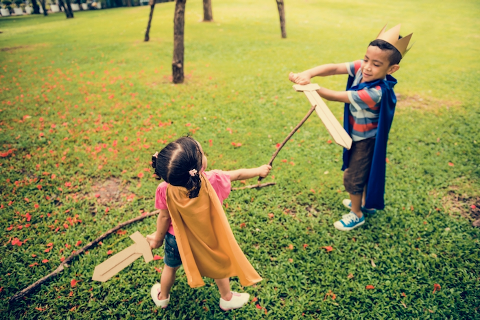 two children play with swords in a garden