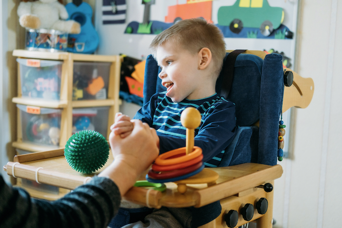 Αγόρι με εγκεφαλική παράλυση κάθεται σε ειδικό κάθισμα και κάνει διάφορες θεραπευτικές δραστηριότητες